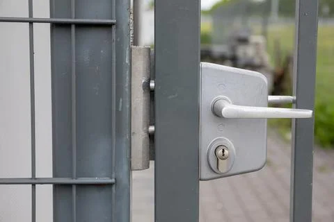 A close-up front view of the white handle on the steel fence gate. Stock Photos
