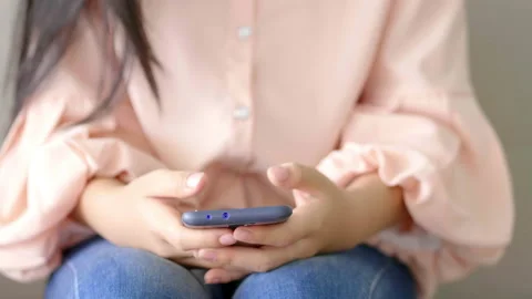 Close up front view of woman using smartphone and sitting on a couch at home Stock Footage 168218329