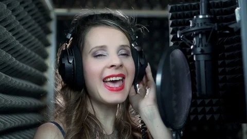Close-up front view of a young singer in headphones singing into a microphone in Stock-Footage 119203661