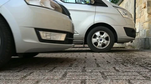 Close up of front wheel of a car as it drives forwards into a parking space w Vidéo 151693525