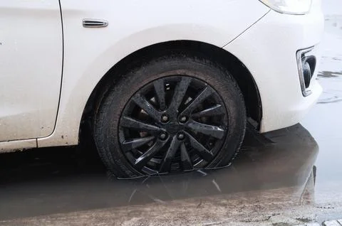 A close-up of the front wheel of a car that stands on the road after a flood Stock Photos