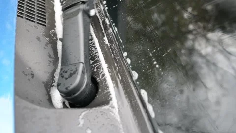 Close-up of a front windshield wiper sweeping away water and foam on a car Video stock 323250565