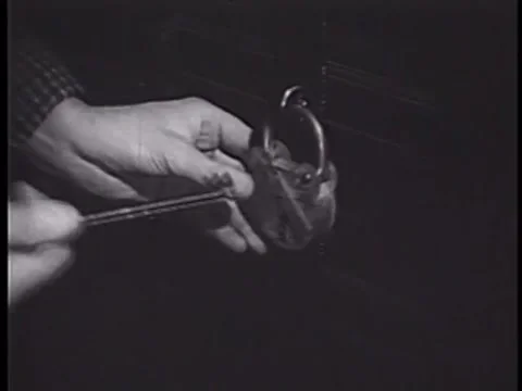 Close-up of frustrated man trying to open padlock, 1950s Stock Footage 64630064