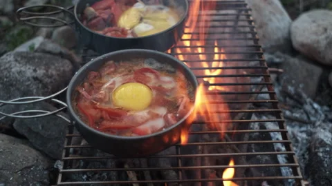 Close up of fry eggs and vegetables in frying pan on bonfire Stock Footage 271551498