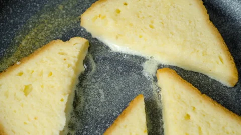 Close-up frying bread slice in egg on frying pan cooking toasts on kitchen at Stock Footage 313133663
