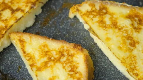Close-up frying bread slice in egg on frying pan cooking toasts on kitchen. Stock Footage 313134729