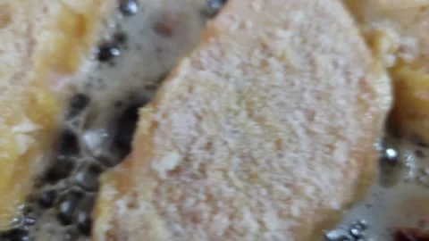 Close-up of frying breaded meat schnitzel in hot bubbling oil in a pan Stock Footage 335572484