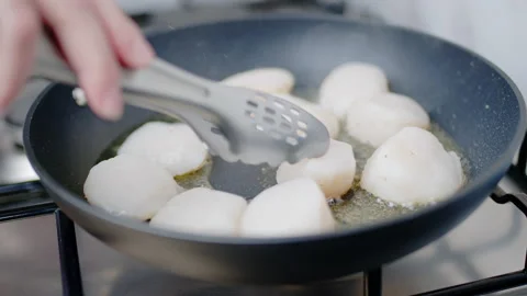 Close-up of frying lots, multiple scallops in oil in a pan on a gas stove in 4K. Stock Footage 138060029
