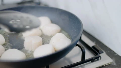 Close-up of frying lots, multiple scallops in oil in a pan on a gas stove in 4K. Stock Footage 138061913