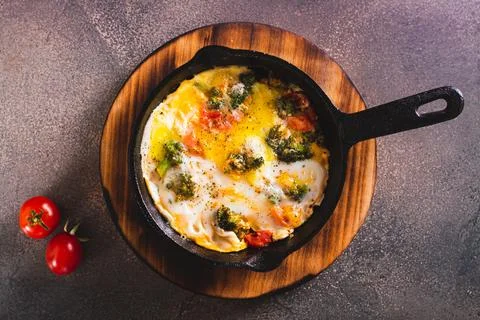 Close up of frying pan with scrambled eggs with broccoli and tomatoes on a .. Stock Photos