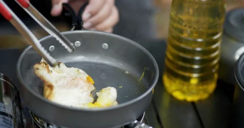 Close-up of frying a tasty fried egg in a hot pan at the campsite.  Stockbeeldmateriaal 199176995