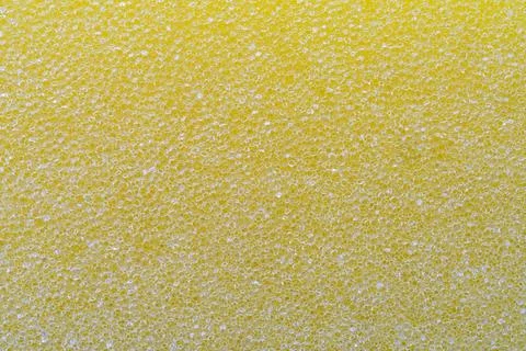 A close-up, full frame shot of a bright yellow sponge's porous texture. Stockfoto's