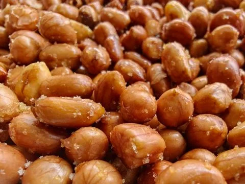 Close-up full frame texture of crispy fried peanuts sprinkled with salt crystals Stockfoto's