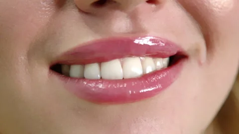Close up of full glowing pink lips of young woman breaking into a smile Stock Footage 257946516