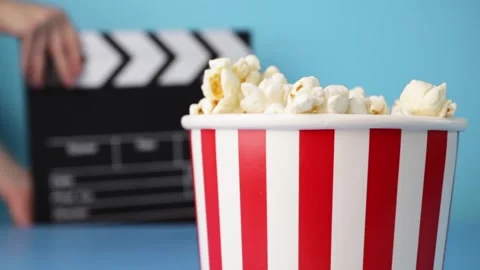 Close-Up of Full Popcorn Bucket with Red and White Stripes and Movie Clappe.. Video stock 309453965