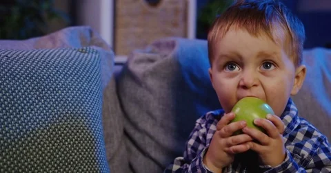 Close up of the funny small boy biting a big green apple and chewing it on the Stock Footage 82920744