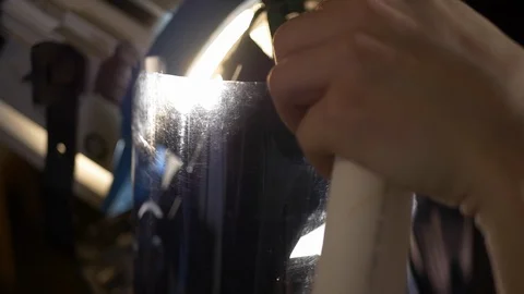 Close-up of gaffer puts blue gel on a fresnel light on video production set. Stock Footage 99427081