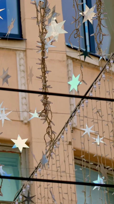 Close-up, garlands of light bulbs and silver stars, sway in the wind, glitter in Video stock 323285559