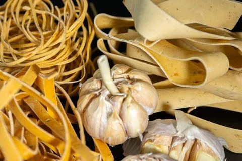 Close-up of garlic bulbs surrounded by uncooked ribbon. Stock-Fotos