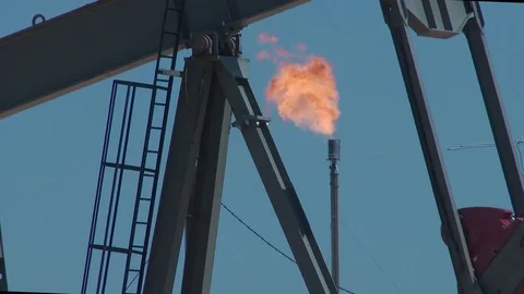 Close of gas flaring through arm of active pump jack, 4K. Stock Footage 80033933