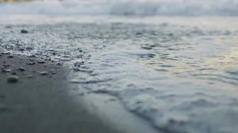 Close-up of gentle foaming sea waves lapping onto a beach. Low angle view. Stock Footage 321750358