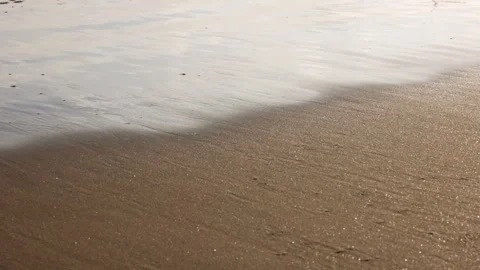 A close-up of gentle ocean waves washing over sand in mesmerising slow motion. Stock Footage 340957348