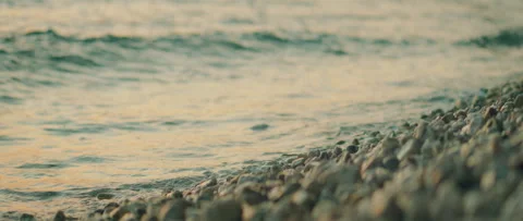 Close-up of gentle waves rolling over pebbles at a seaside in evening Croatia Stock Footage 313015785