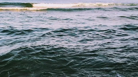 Close-up of a gently rolling steely dark sea with illuminated wave crests. Stock Footage 303979745