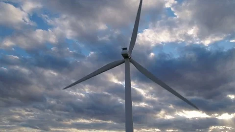 Close up of giant wind turbine turning at sunset under cloudy sky Stock Footage