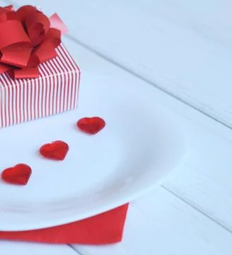 Close up.gift box and red hearts on a white plate. Stock Photos