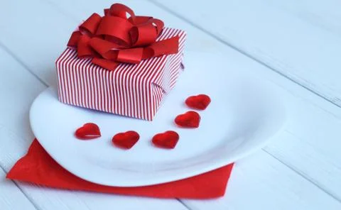 Close up.gift box and red hearts on a white plate. Stock Photos