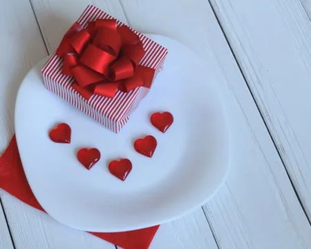 Close up.gift box and red hearts on a white plate. Stock Photos