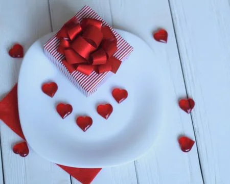Close up.gift box and red hearts on a white plate. Stock Photos