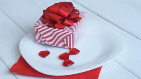 Close up.gift box and red hearts on a white plate. Stock Photos