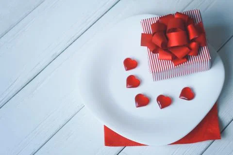 Close up.gift box and red hearts on a white plate. Stock Photos