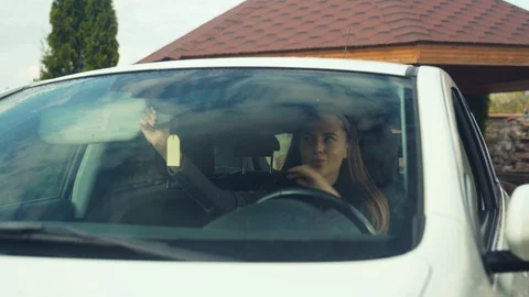 Close-up. The girl in the car, looks in the upper mirror, straightens her hair Stock Footage 129152553
