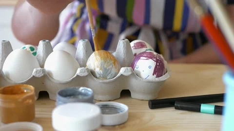 Close up of girl coloring Easter eggs at home using paints and brush. Video stock 169971337