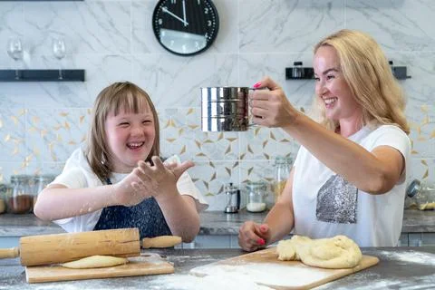Close-up of a girl with down syndrome and her charming mother, baking dough p Stock Photos