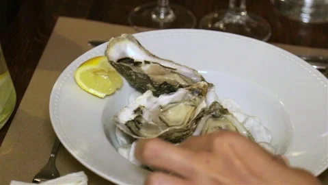 Close-up, the girl eats oysters with a seashell fork in the restaurant. Video stock 96357308