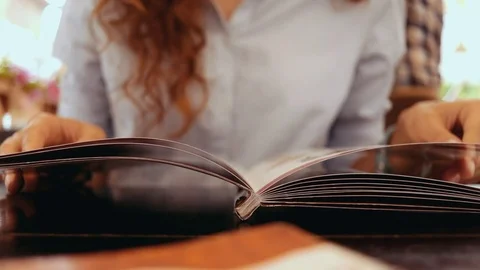 Close-up of the girl leafing through the menu Stockbeeldmateriaal 72565702
