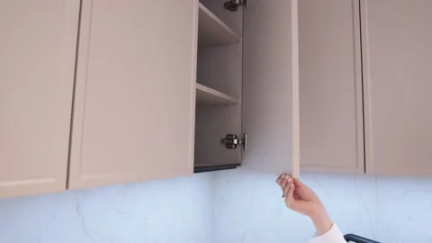 Close-up girl opens the doors in the kitchen cabinet. Modern classic kitchen int Stock Footage 240357797