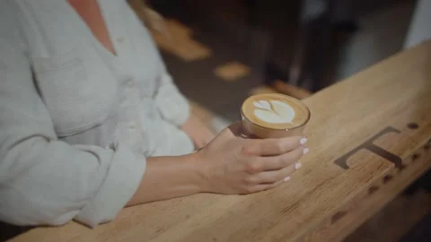 Close up of girl placing down latte on cafe counter, latte art 库存影片 220310029