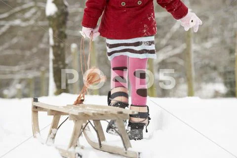 Close up of girl pulling sledge through winter landscape Stock Photos