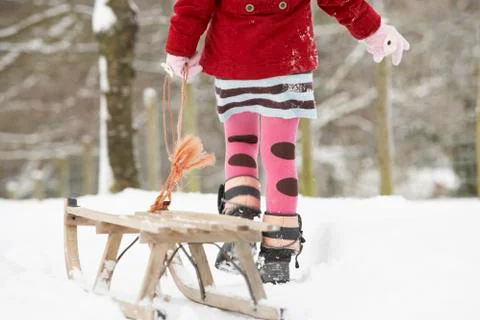 Close up of girl pulling sledge through winter landscape Stock Photos