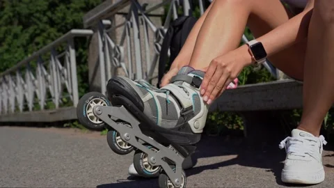Close-up girl putting on inline skates rollers in public park in summer. Youth Stock Footage 237594975