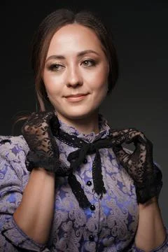 A close-up of a girl smiling, she adjusts the collar in lace gloves on a blue Stock Photos