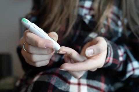 Close-up of a girl using a lancing device to prick her finger for a blood s.. Stock Photos