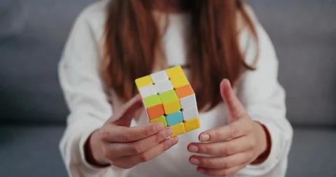 Close up of girl using Rubik's Cube while sitting on couch Stock Footage 132332470