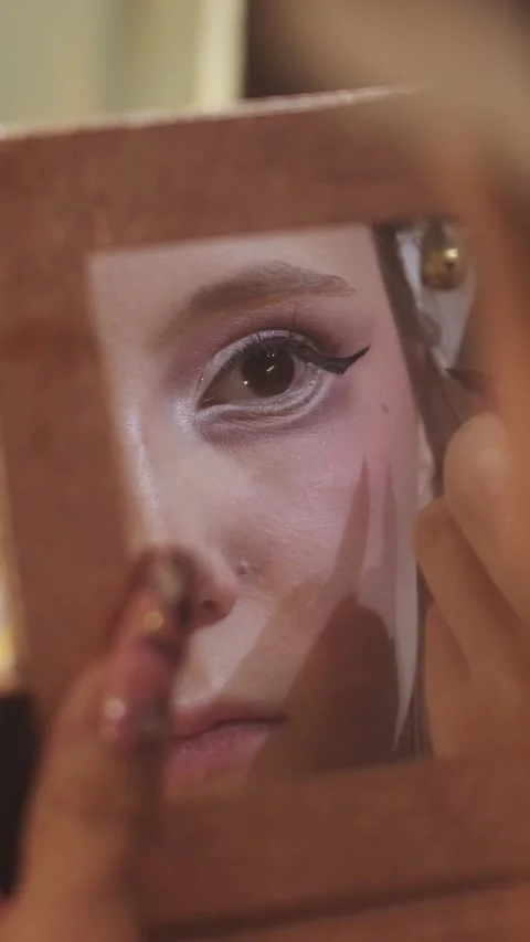 Close-up of a girls eye reflected in the mirror while she is applying liquid 動画素材 328075602