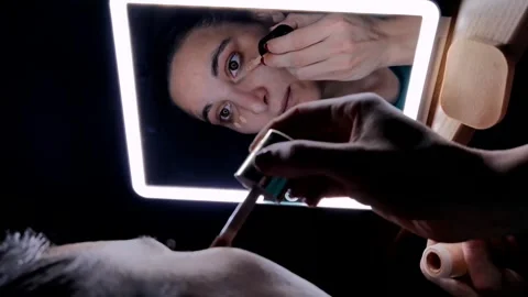 Close-up of a girl's face in front of the mirror while she is putting foundation Stock Footage 250186533